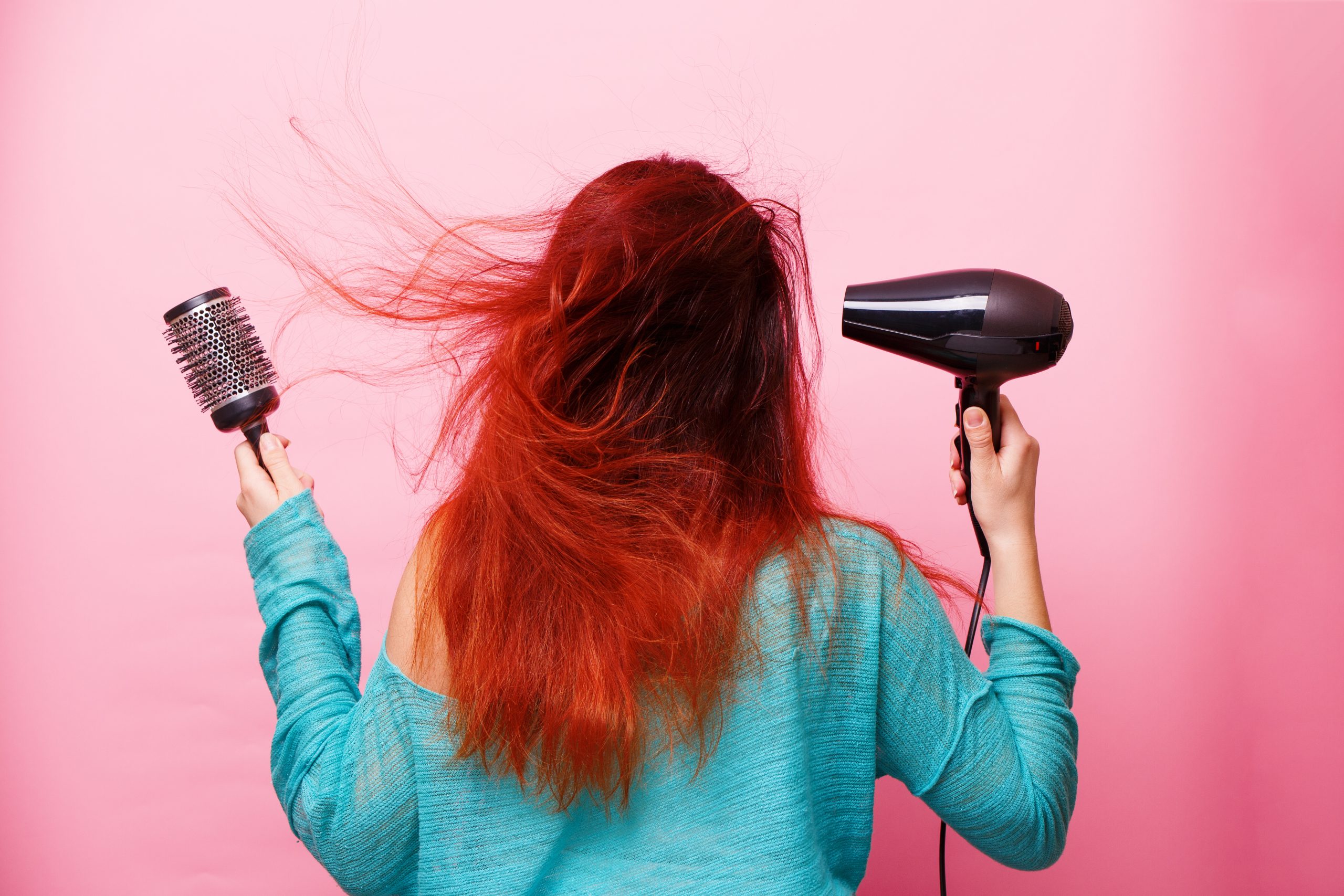 Mão de menina segurando o secador de cabelo.